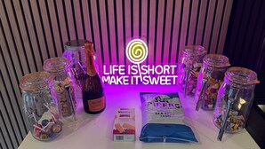 Presentación de productos alimenticios, incluyendo botes de caramelos, una botella de Maschio Prosecco y un paquete de Walker's Shortbread Fingers.