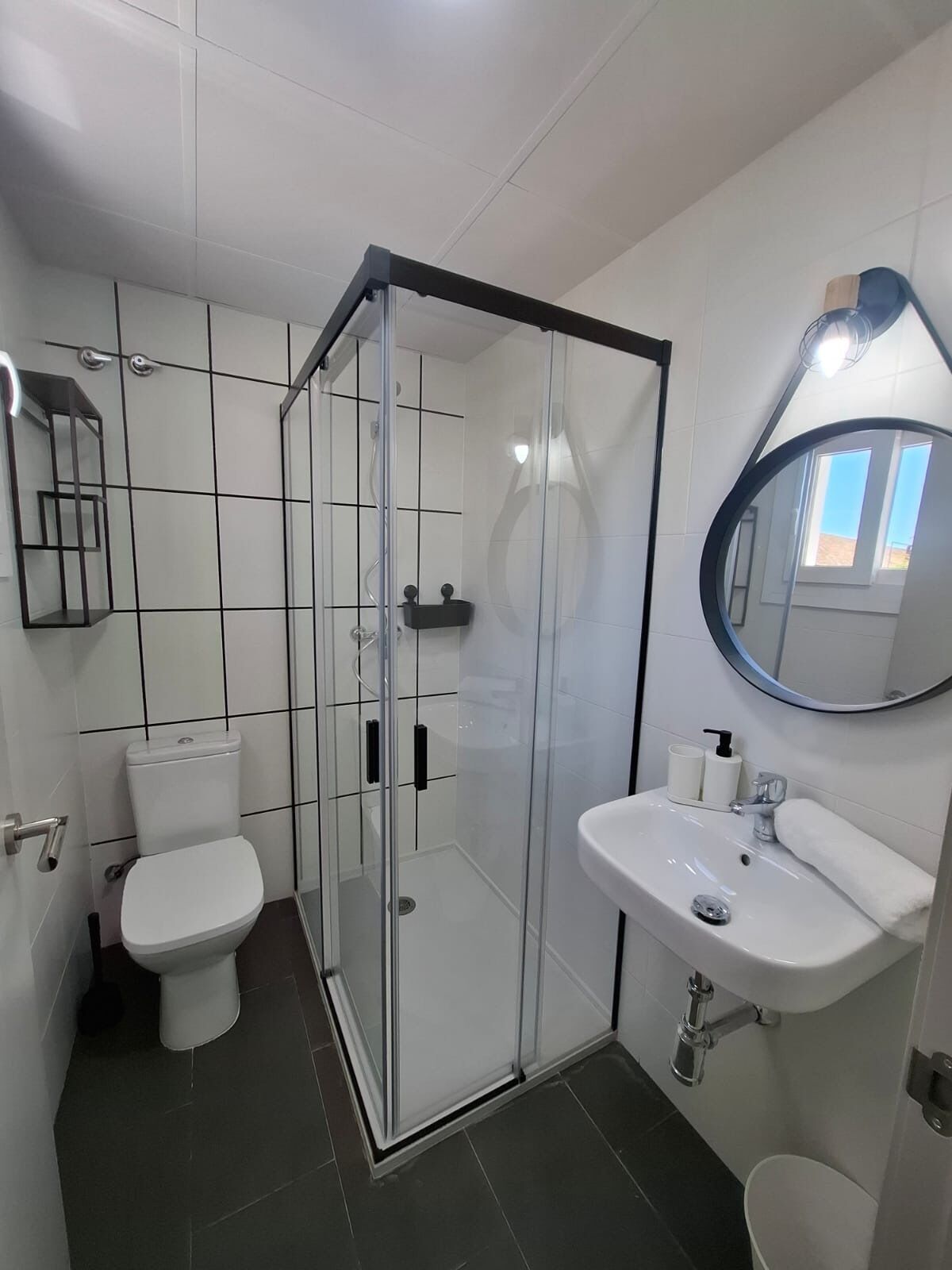 A modern bathroom with a glass-enclosed shower, a white sink, and a toilet.