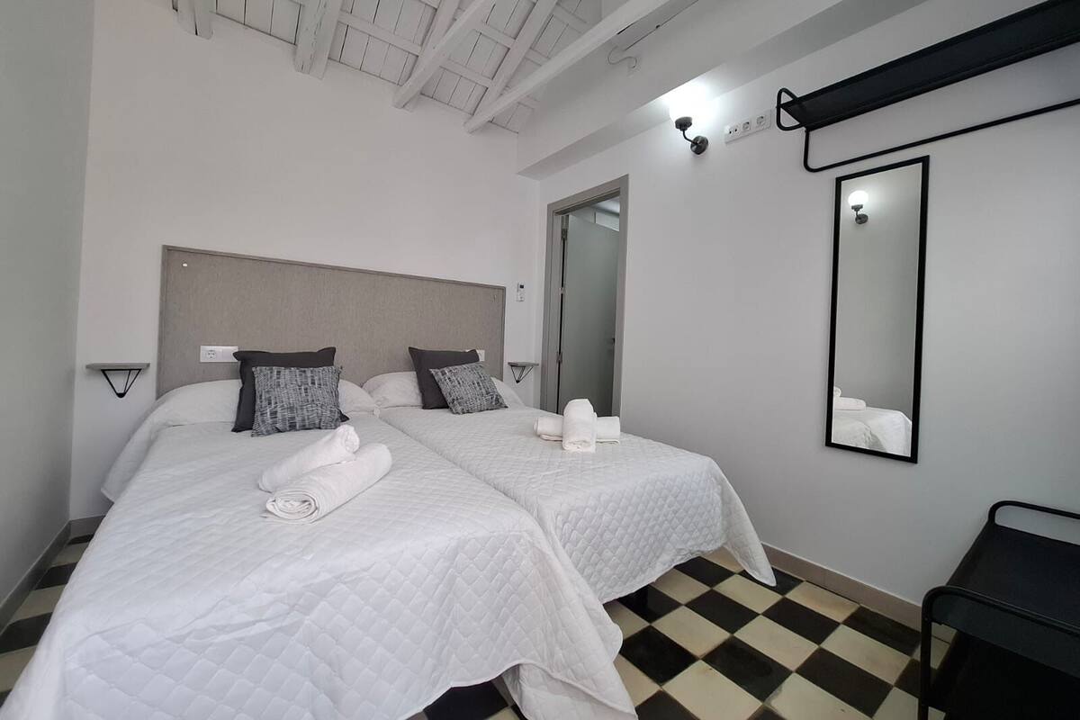 A hotel room with two beds, a large mirror, and a checkered floor.