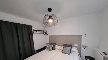 Una habitación de hotel moderna con una cama grande, mesitas de noche, un escritorio y una lámpara colgante.