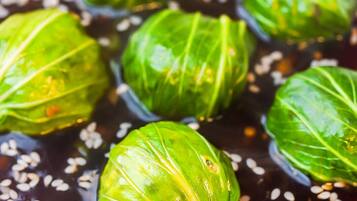 A bowl of cabbage rolls in a dark sauce with sesame seeds.