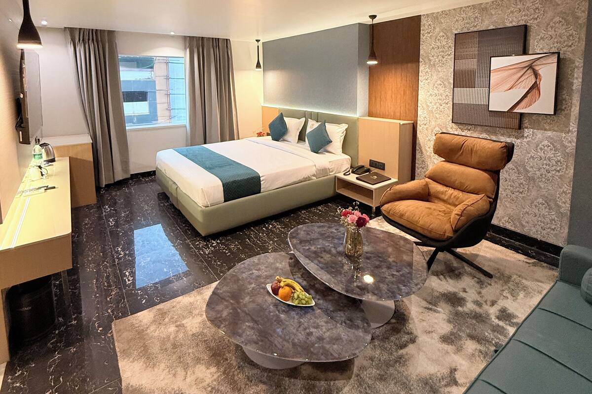 Una habitación de hotel moderna con una cama grande, una zona de estar con una mesita de café, un sofá, un escritorio y un baño.