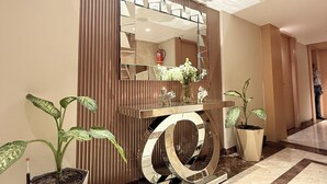 Un vestíbulo moderno con un espejo grande, una consola y dos plantas en macetas.