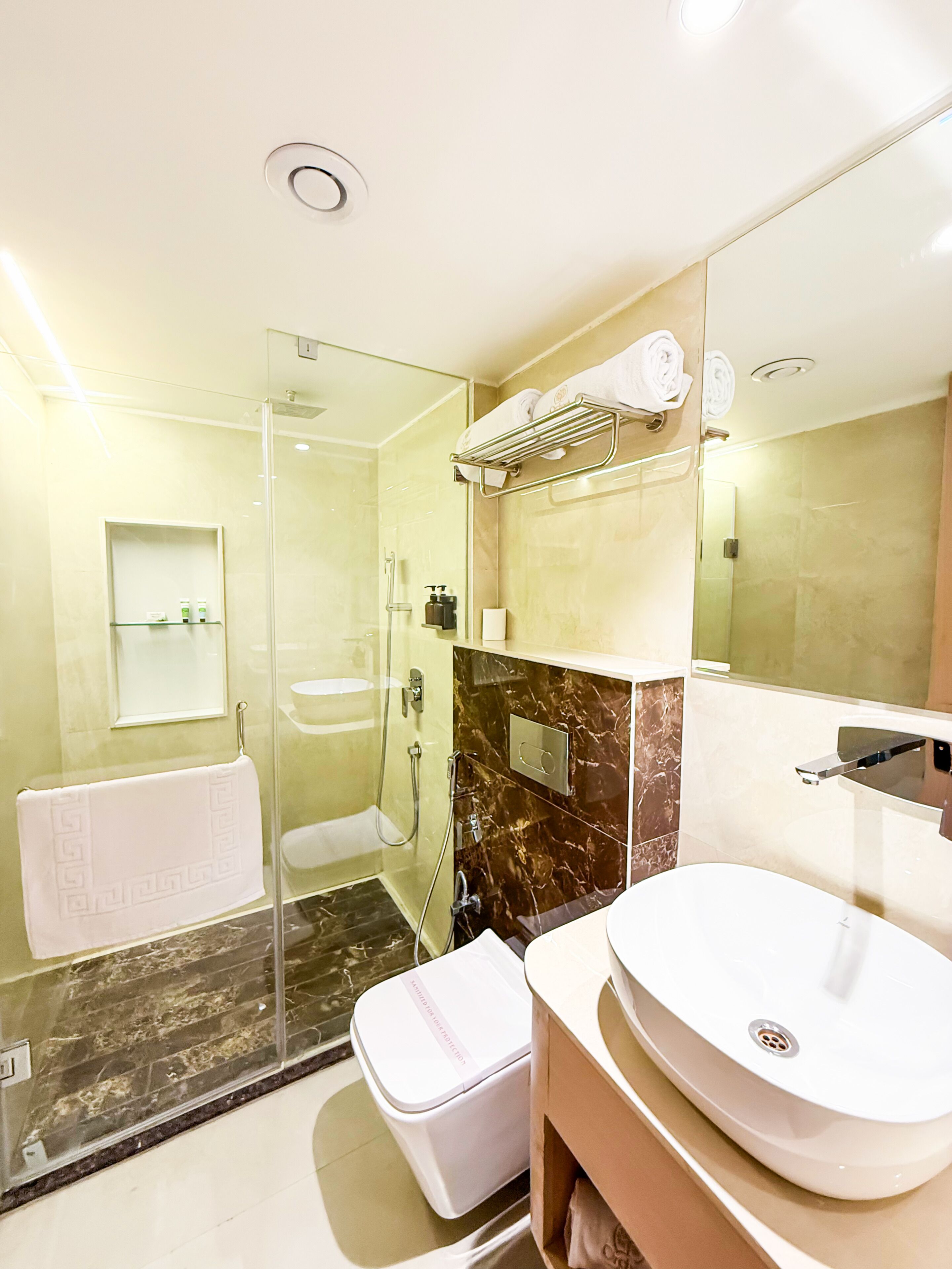A modern bathroom with a glass-enclosed shower, a white sink, and a marble backsplash.
