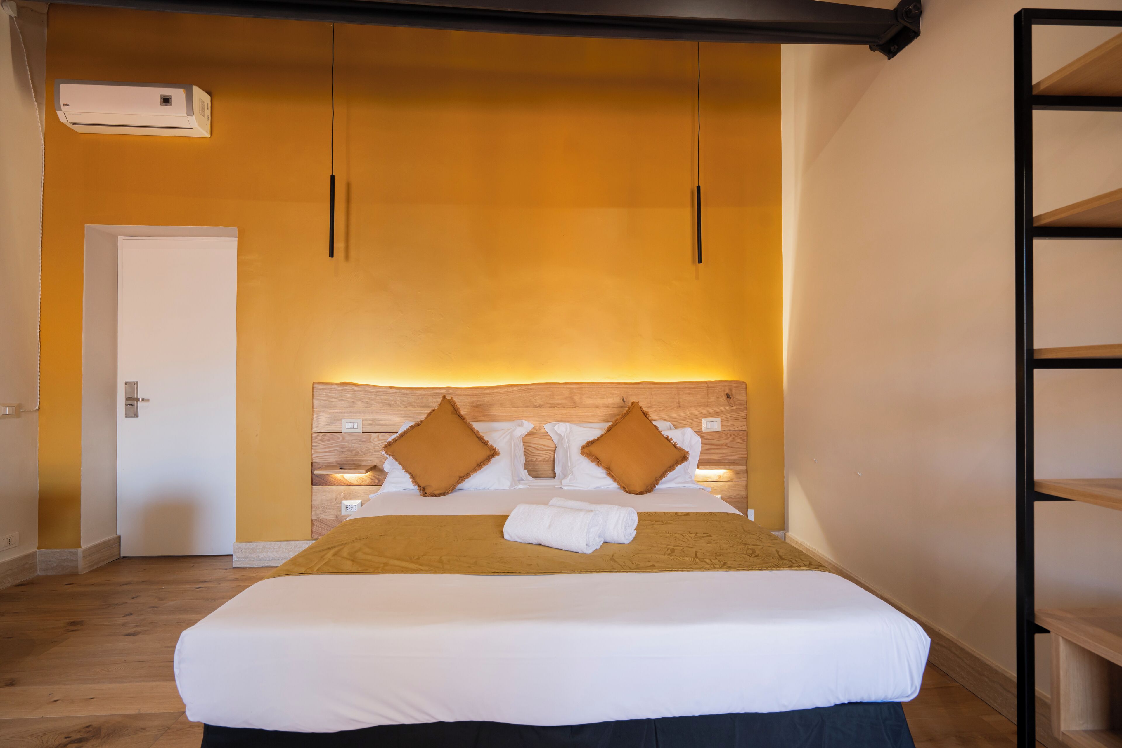 Une chambre d’hôtel avec un grand lit, une tête de lit en bois et une porte blanche.