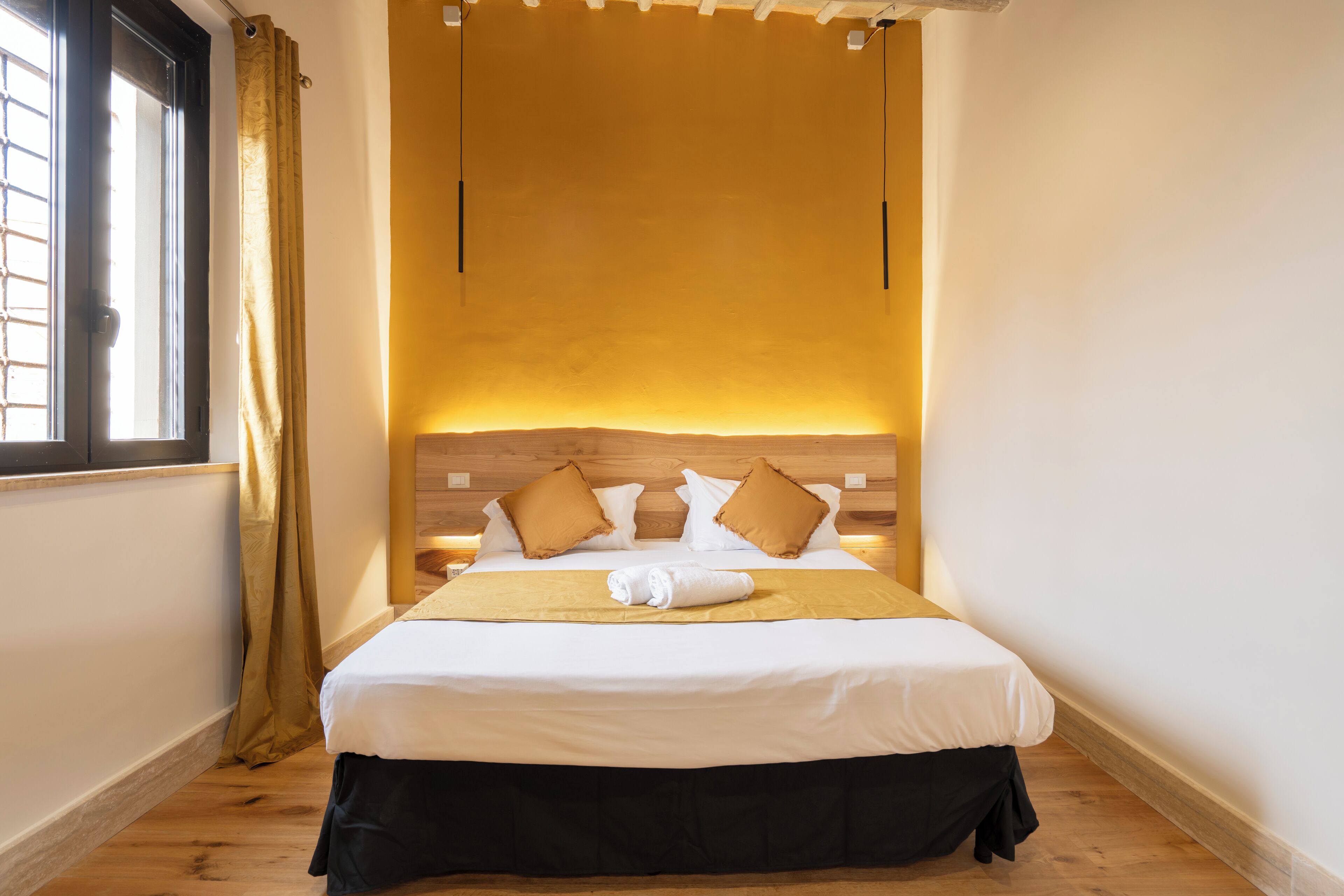 Une chambre d’hôtel avec un lit, une fenêtre avec des rideaux et un plancher en bois.
