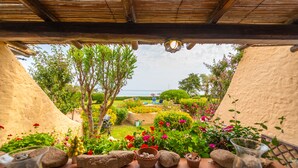 Ein Garten mit Meerblick, mit einer Pergola, Kübelpflanzen und einem kleinen Tisch mit einer Schüssel.