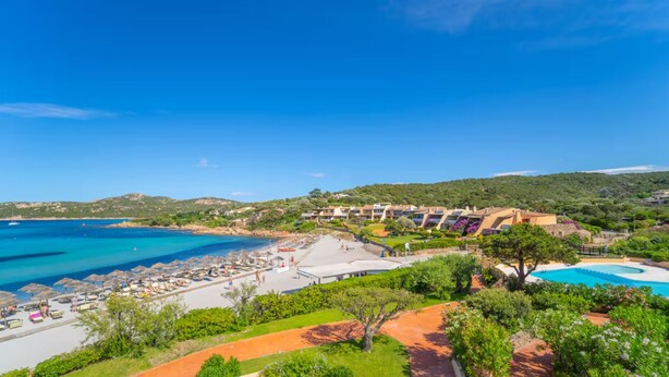 Ein Küstenort mit Strand, Pool und üppiger Bepflanzung.