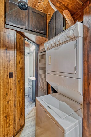 A compact kitchen with wooden cabinetry, a built-in oven, and a washing machine.