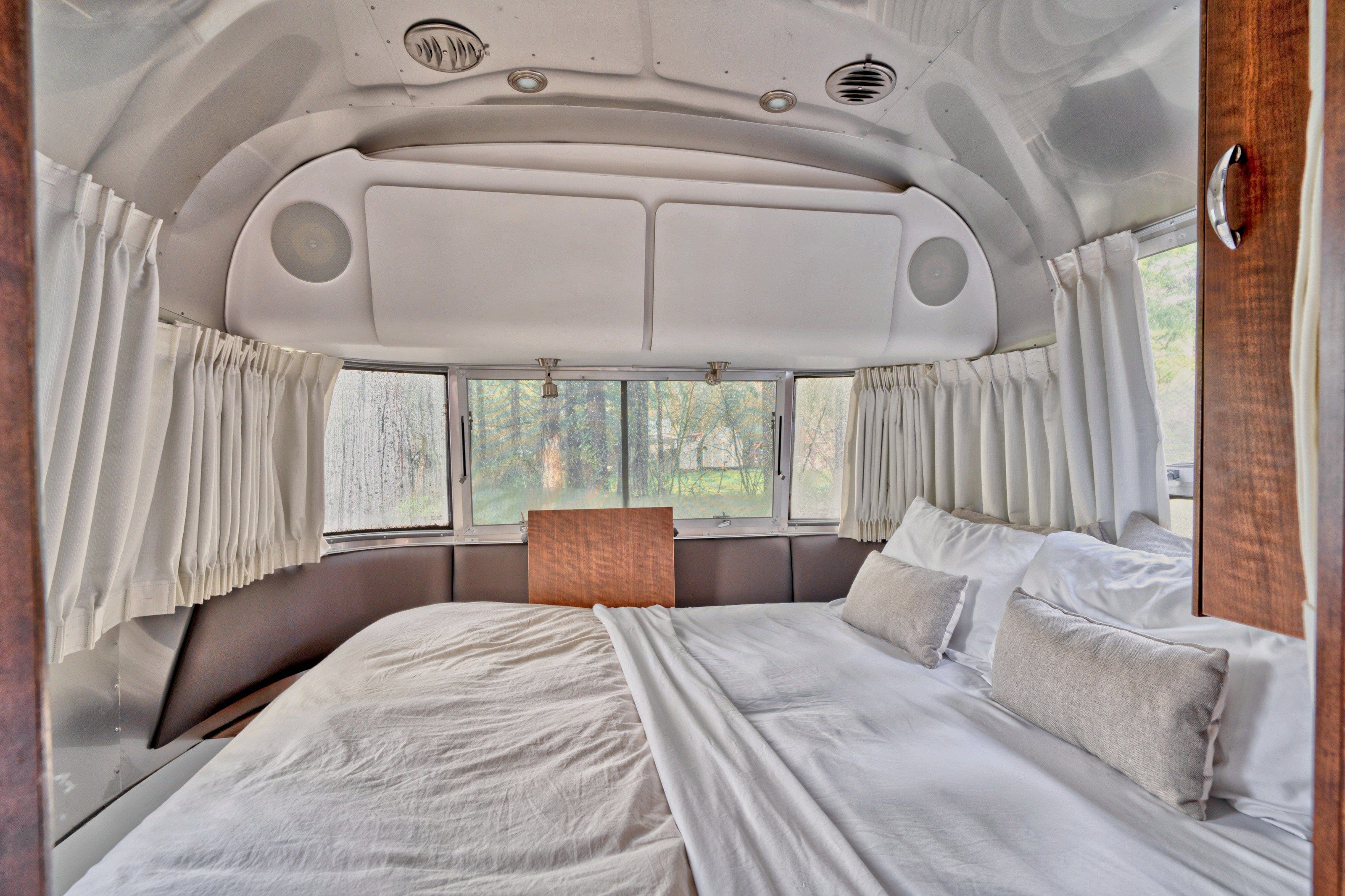 A bed with white linens and pillows, a headboard, and a window with curtains.