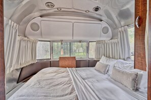 A bed with white linens and pillows, a headboard, and a window with curtains.