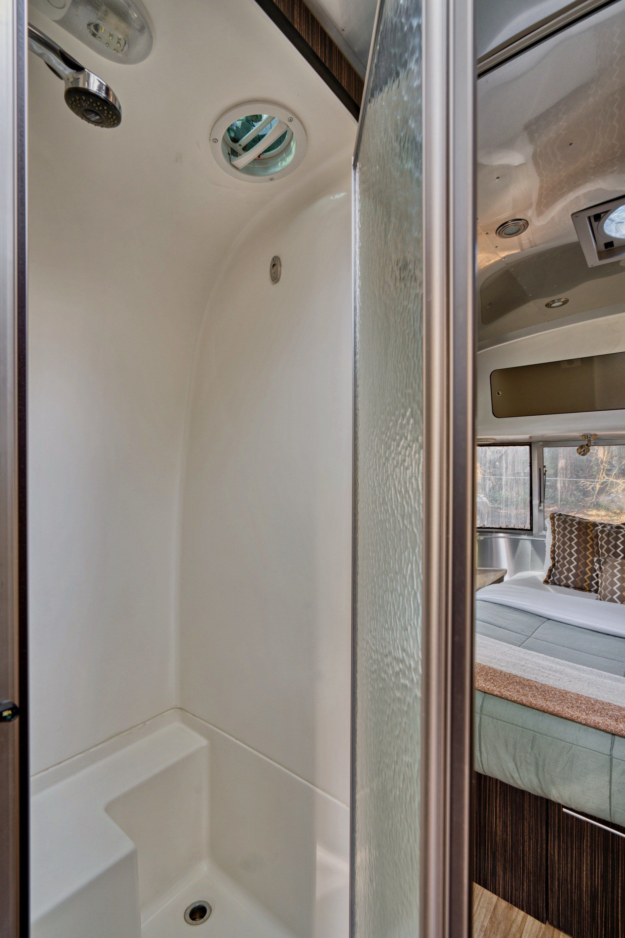A compact shower area with a built-in seat and a small window.