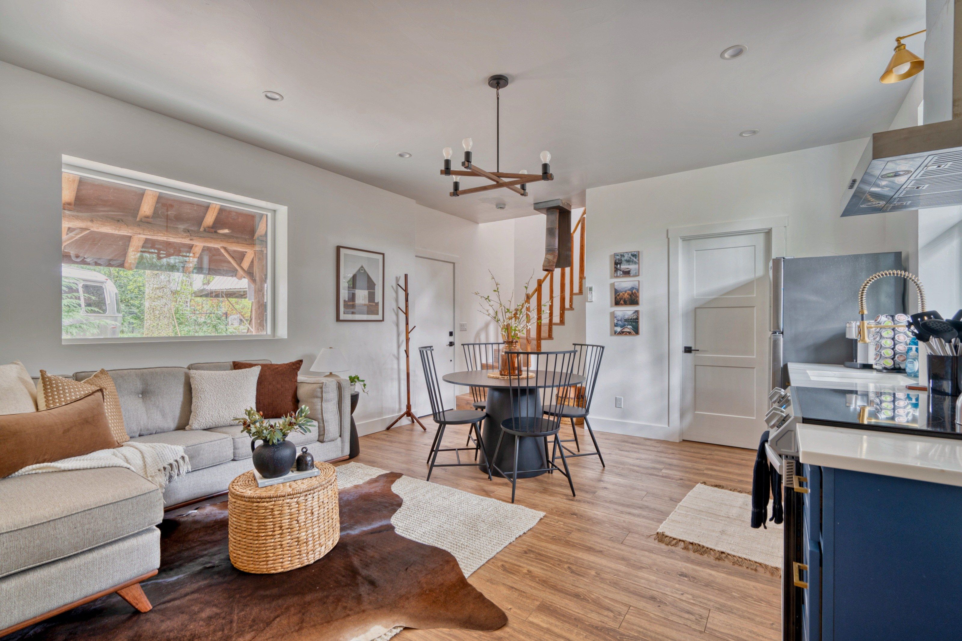 A modern living room with a sofa, coffee table, and dining area with chairs.