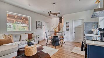 A modern living room with a sofa, coffee table, and dining area with chairs.