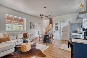 Un salon moderne comprenant un canapé, une table basse et un coin repas avec des chaises.