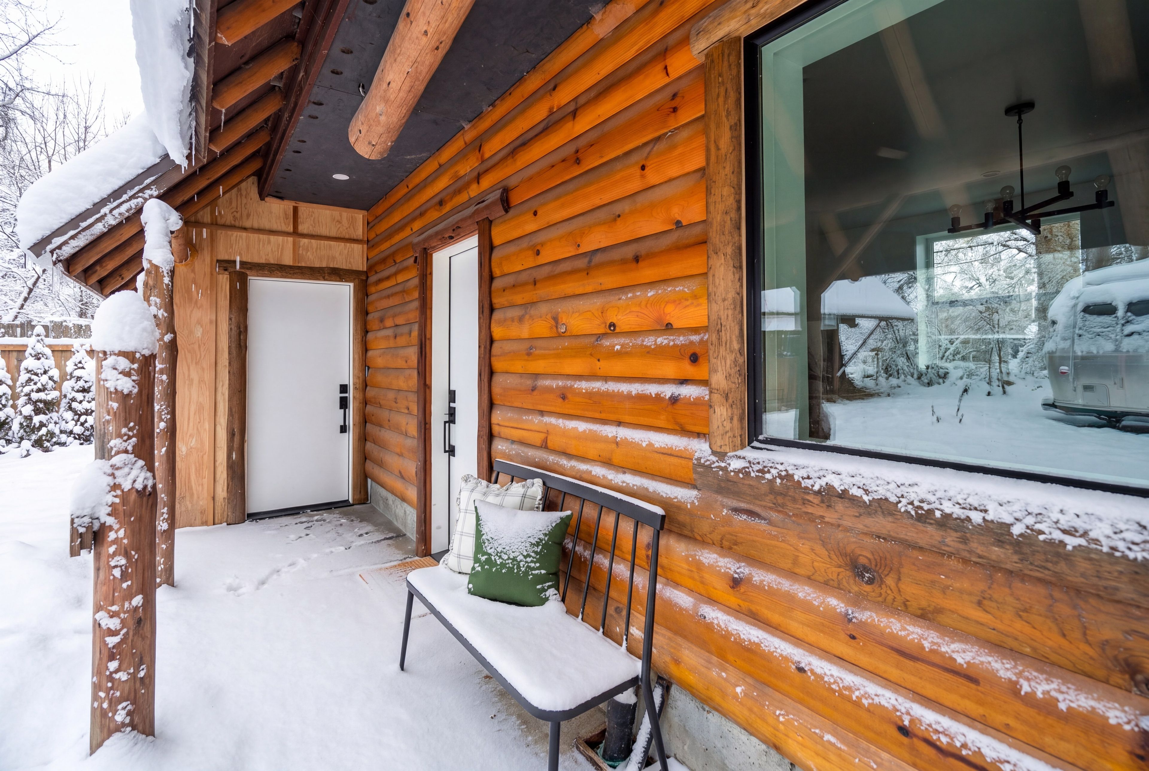 A wooden cabin with a bench and a door, surrounded by snow.