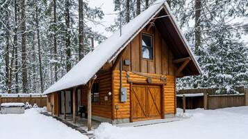 The Forest Cabin from outside, with its covered entry and hot tub, in winter.