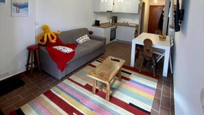 Ein kompakter Wohnbereich mit Sofa, Couchtisch, Esstisch und Küchenzeile.