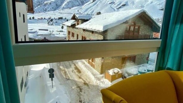 Ein Zimmer mit einem großen Fenster und Blick auf eine verschneite Berglandschaft.