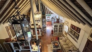 A spacious loft with high ceilings, exposed beams, and a cozy fireplace.