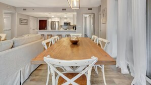 A modern dining area with a wooden table, white chairs, and a central island with a bowl.