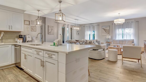 A modern kitchen with white cabinetry, a central island, and pendant lighting.