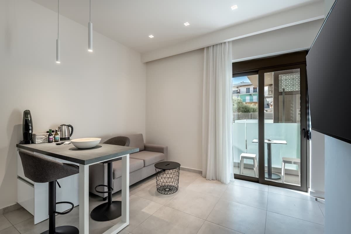 Een moderne keuken met een eethoek, een bank en een balkon met buitenmeubels.