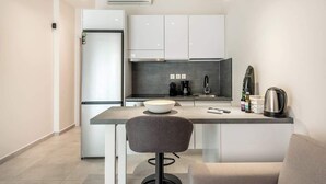 Een moderne keuken met witte kastjes, een roestvrijstalen koelkast, een koffiezetapparaat en een waterkoker op het aanrecht.