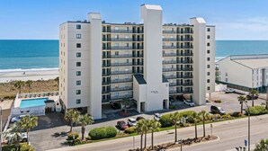 A multi-story hotel with balconies, a swimming pool, and a view of the beach and ocean. - Beach Club I Unit 5F - Oceanfront! (North Myrtle Beach)