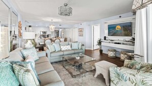 A spacious living room with a large sofa, a coffee table, and a television. - Beach Club I Unit 5F - Oceanfront! (North Myrtle Beach)