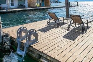 Um cais de madeira com um espaço para barcos, duas cadeiras e uma mesa.