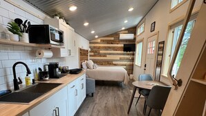 A compact, modern kitchen with white cabinets, a wooden countertop, and a built-in microwave. - Orange Poppy - Seward Alaska Modern Forest Tiny Home Retreat Near Kenai Fjords (Seward)