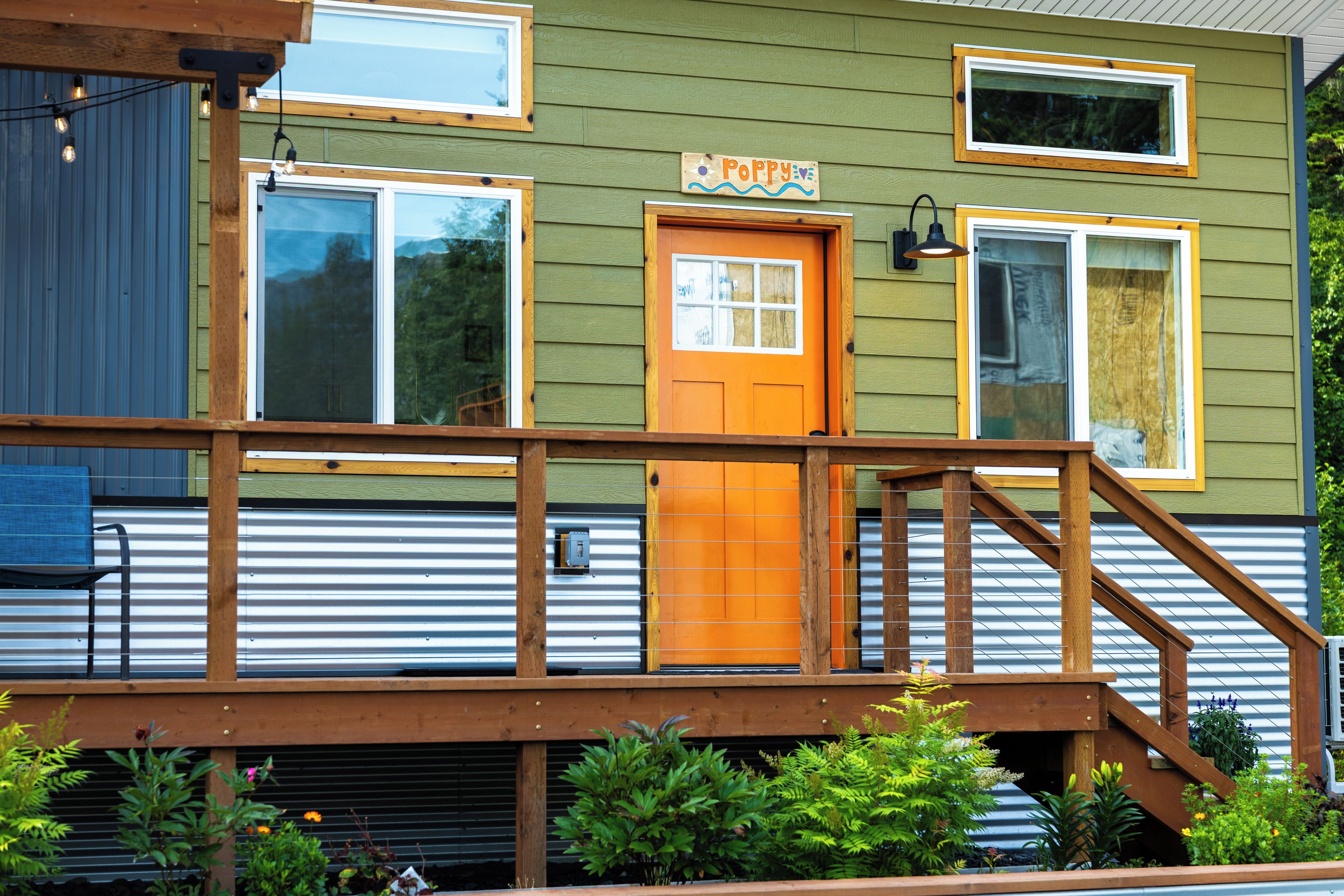 A wooden deck with a railing, a wooden door, and a window with a sign above it.