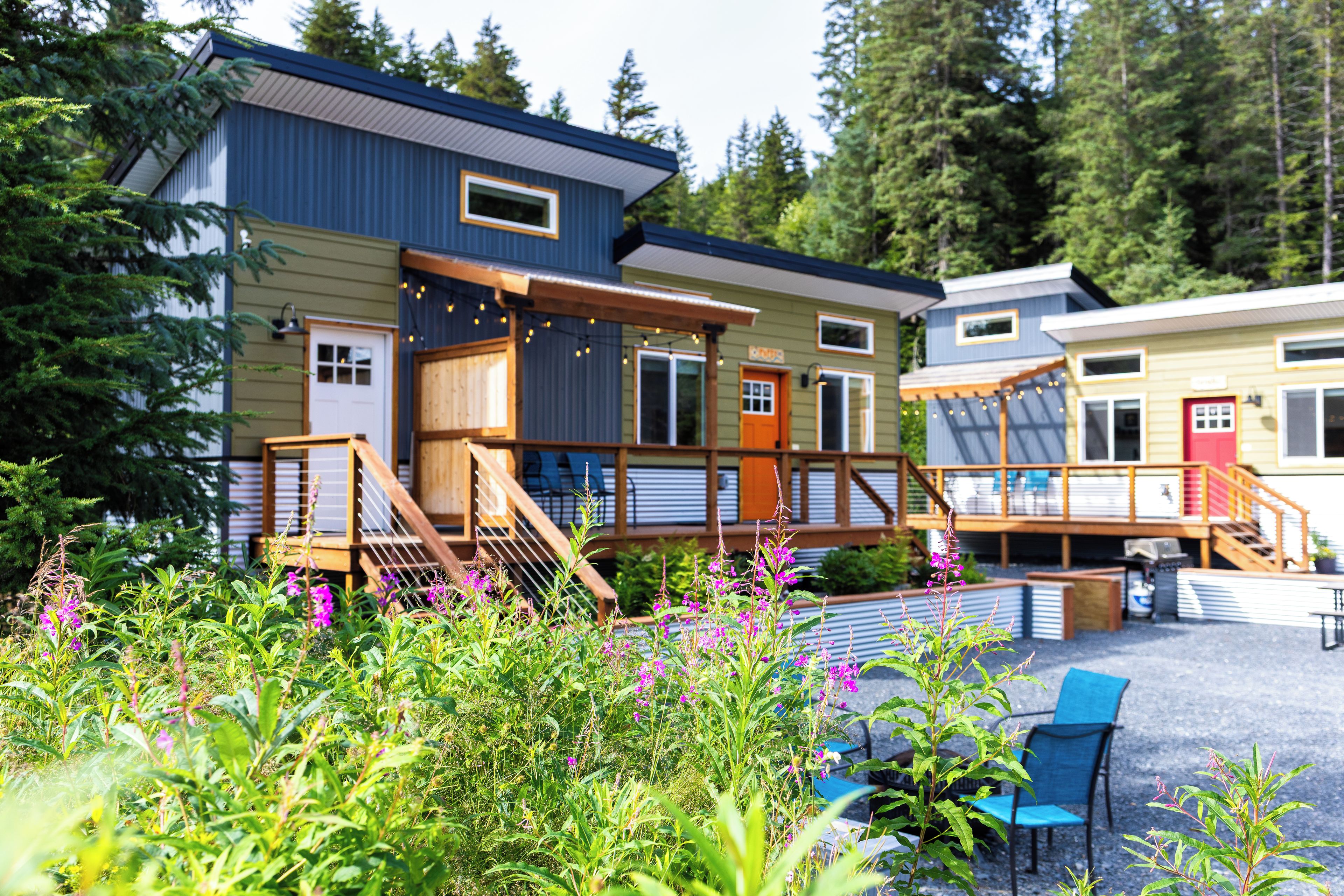 A row of cabins with wooden decks and a garden area with various plants and flowers.