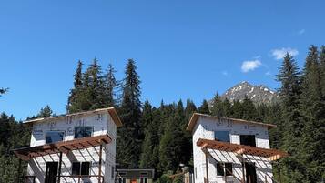 Due cabine con travi a vista in legno e una montagna sullo sfondo.