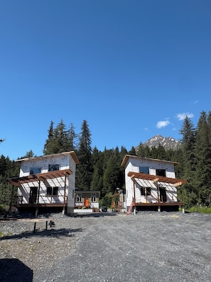 Two cabins with exposed wooden beams and a mountain in the background. - Orange Poppy - Seward Alaska Modern Forest Tiny Home Retreat Near Kenai Fjords (Seward)
