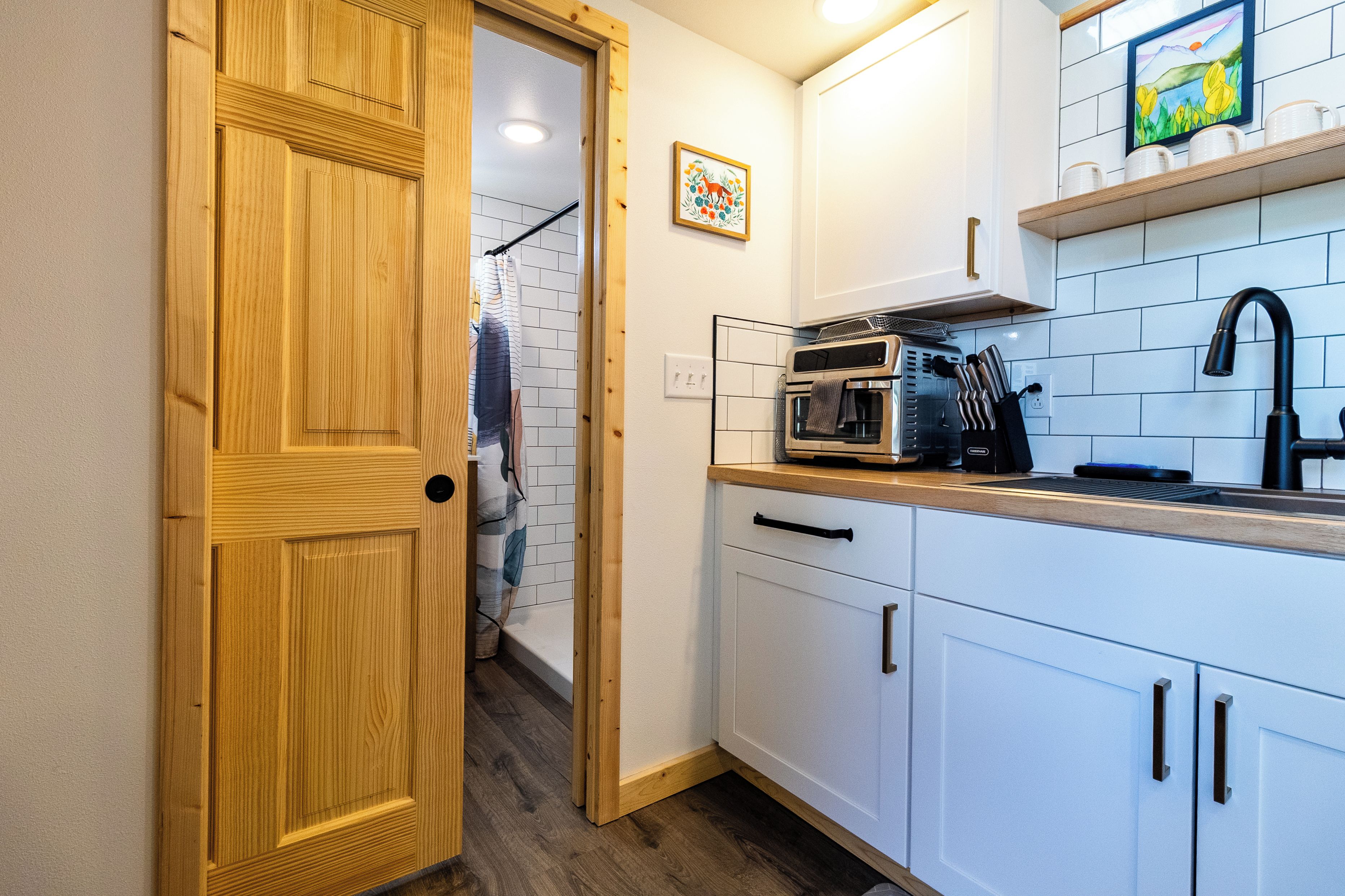 Una cucina compatta con mobili bianchi, un forno a microonde e un lavandino.