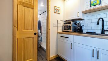 Una cucina compatta con mobili bianchi, un forno a microonde e un lavandino.