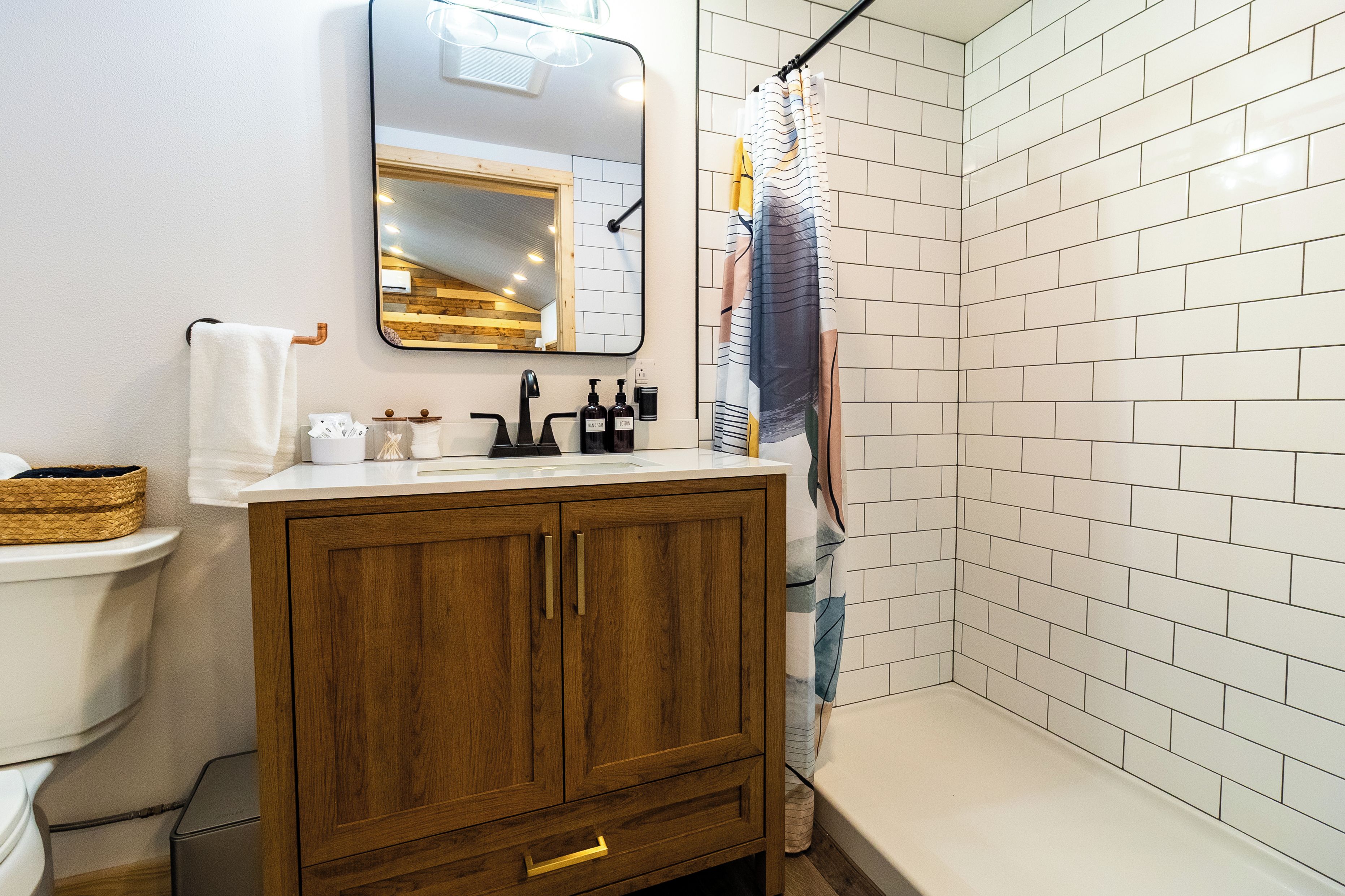 A bathroom with a wooden cabinet, a white sink, a mirror, and a shower curtain.