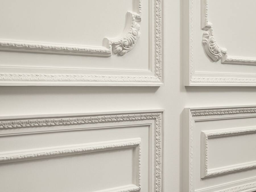 A wall with ornate white moldings and paneling.