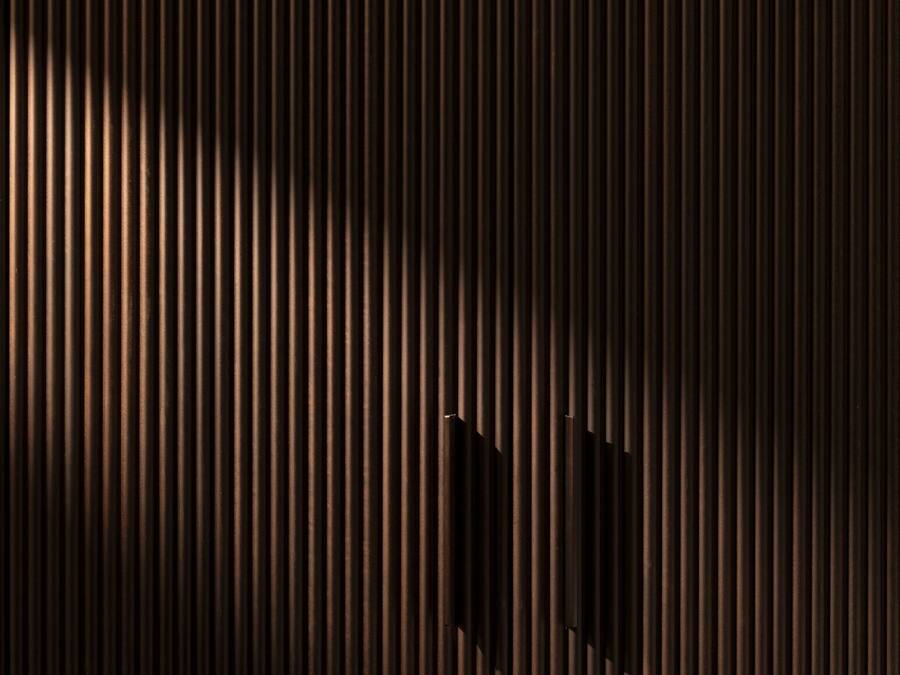 A textured wall with vertical lines and a small rectangular object in the center.