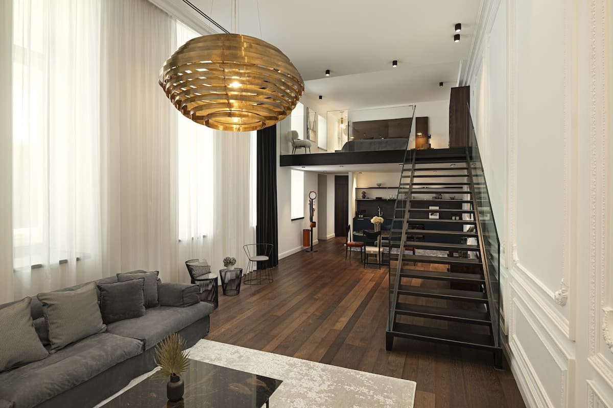 A modern living room with a grey sofa, a coffee table, and a large pendant light.