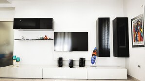 A modern living room with a flat-screen TV, black speakers, and a white entertainment unit. - Casa Perini in Chioggia (Chioggia)