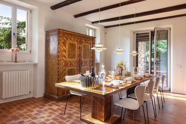 Comedor con mesa de madera dispuesta para cuatro, un mueble grande y vistas al exterior.