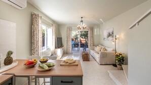 A modern kitchen with a wooden table, fruit bowl, and a TV. - Larnaca Oneiro Seaside Villa (Pervolia)