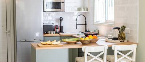 A modern kitchen with a stainless steel refrigerator, a microwave, and a wooden island with chairs.