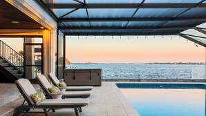 An infinity pool with lounge chairs and a view of the sea. - Riverfront Riviera Outdoor TV's/Hotub/Tanning Deck (Cape Coral)