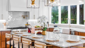 A modern kitchen with white cabinets, a large island, and two pendant lights. - Riverfront Riviera Outdoor TV's/Hotub/Tanning Deck (Cape Coral)