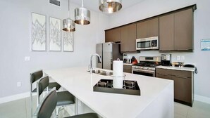 A modern kitchen with stainless steel appliances, a central island with seating, and pendant lighting. - Spacious 3-bedroom apartment with AC, WiFi in amazing Kissimmee (Kissimmee)
