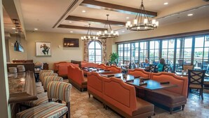 A restaurant with hexagonal tiled flooring, orange cushioned booths, and a large window offering a view. - Spacious 3-bedroom apartment with AC, WiFi in amazing Kissimmee (Kissimmee)